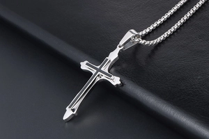 Macro shot of silver and black stainless steel cross pendant on leather surface