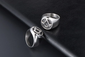 Macro shot of silver titanium steel rings with engraved Masonic symbols on black leather