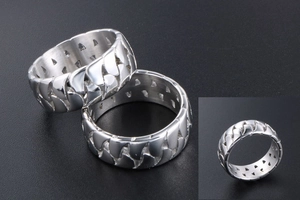 Detailed macro view of silver titanium steel rings featuring unique hollow chain weave texture