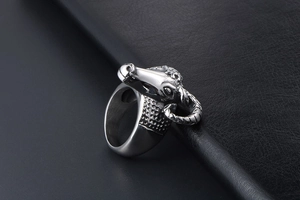 Detailed view of goat head metal ring with spiral horns on black leather background
