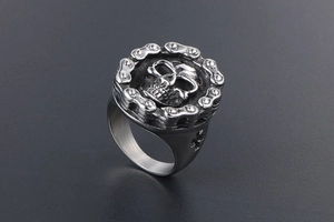 Close-up of vintage steel skull ring featuring detailed bicycle chain relief and punk design