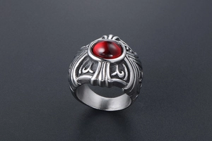 Close-up of gothic stainless steel ring with large oval red gemstone and relief patterns