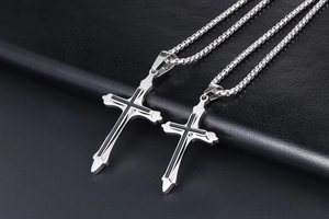 Detailed macro view of two sizes of silver cross pendants on black leather texture