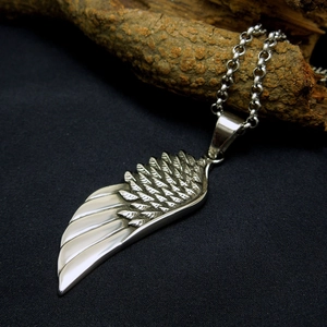 Retro stainless steel wing pendant necklace with silver feather details on driftwood
