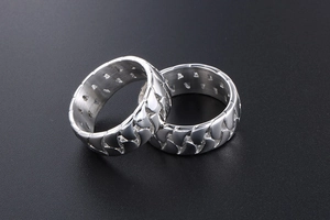 Detailed close-up of two silver titanium rings with openwork cuban chain texture design