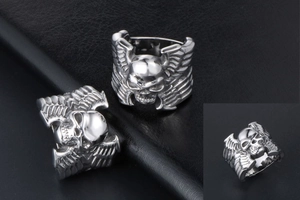 Détail d'une bague punk en acier inoxydable avec crâne et motifs d'ailes ciselés