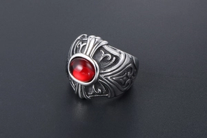 Close-up of gothic stainless steel ring with a large red oval stone and engraved patterns