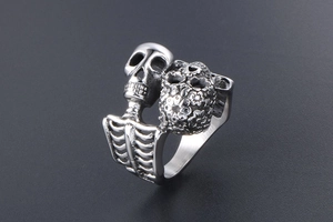 Detail of gothic silver skull ring with floral engraving and skeletal rib cage band
