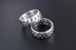Detail of silver Cuban link rings showing polished metal chain texture on a black background