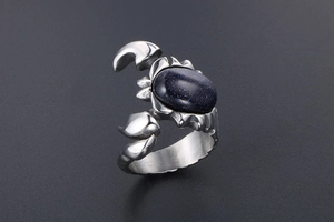 Macro view of a silver scorpion ring with an oval blue sandstone inlay in punk style