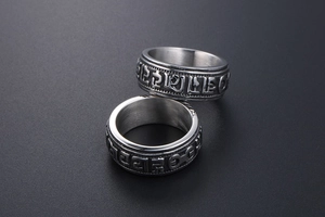 Detail of vintage punk titanium steel rings featuring embossed Six Syllable Mantra characters