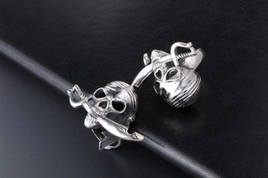 Détail d'une bague tête de mort pirate en acier inoxydable avec un sabre dans la bouche