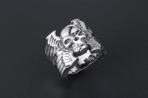 Détail d'une bague tête de mort vintage en argent avec des ailes gravées de style punk