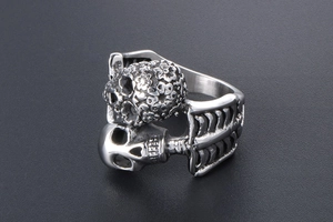 Macro detail of silver skull ring featuring floral carvings and human rib bone band