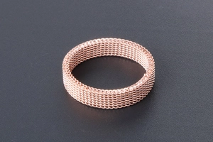 Macro shot of rose gold woven mesh ring texture showing industrial braided steel pattern
