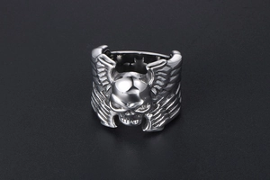 Détail macro d'une bague gothique tête de mort et ailes en acier titane poli