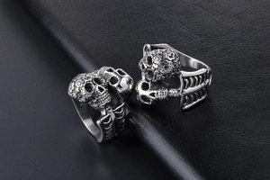 Macro detail of two silver gothic skull rings with rib cage design on black leather