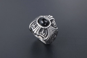 Macro detail of gothic titanium steel ring featuring black gemstone and cross engraving