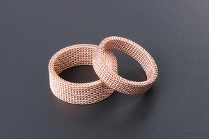 Detail of rose gold titanium mesh rings showing milanese weave craftsmanship and texture