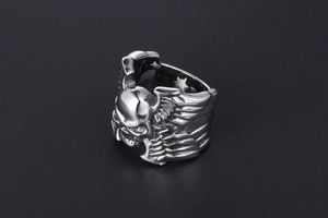 Détail macro d'une bague punk tête de mort avec ailes en acier titane argenté antique