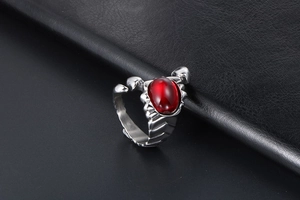 Close-up of gothic scorpion ring featuring a red gemstone on silver textured metal