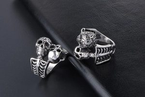 Close-up of gothic skull rings with bone structure on a black leather background