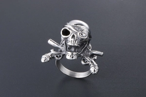 Detail of vintage punk pirate skull ring with crossed muskets in silver finish