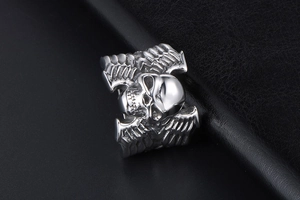 Gros plan sur bague gothique tête de mort avec ailes en acier poli au style vintage