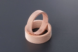 Macro shot of rose gold mesh woven titanium steel rings with detailed texture