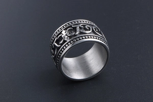 Close-up of vintage titanium steel wide ring with embossed scroll patterns and cross details