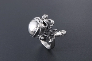 Macro shot of silver pirate skull ring with crossbones detail on dark textured surface