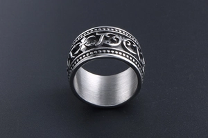 Close-up of wide titanium steel ring with gothic lettering and vintage floral relief