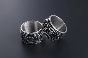 Macro view of vintage fleur-de-lis engraving and brushed texture on wide steel ring