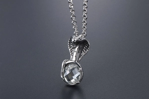 Close-up of cobra pendant with a large clear gemstone and cross-patterned metal scales