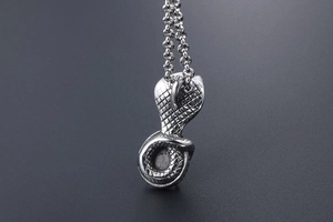 Macro shot of cobra pendant with detailed scale texture on a stainless steel chain