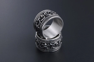 Macro detail of gothic style stainless steel rings with vintage embossed scroll patterns