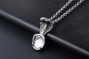 Macro shot of punk cobra pendant with large crystal and cross on black leather background