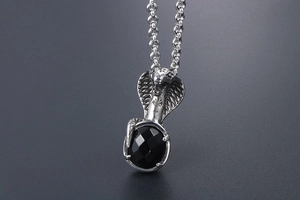 Macro shot of cobra pendant with intricate cross patterns and a faceted black gemstone