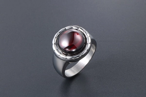 Vue macro d'une bague argentée vintage ornée d'une pierre de grenat rouge profond
