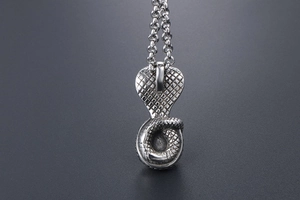Macro shot of cobra snake pendant showing detailed scale texture and retro steel finish