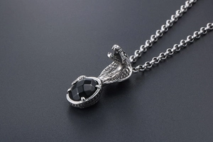Detail of cobra pendant necklace with black faceted gemstone and silver scales texture