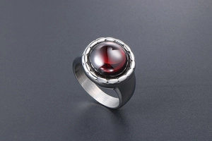 Vue macro d'une bague vintage en acier titane avec grenat rouge rond et bord cranté