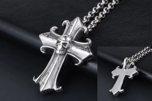 Detailed view of Gothic cross pendant with skull center and metal chain on black background