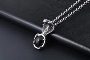 Macro detail of gothic cobra pendant featuring a black gemstone and steel cross engraving