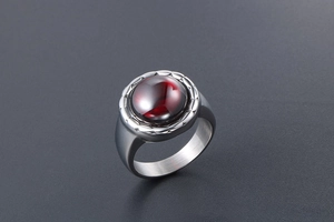 Vue macro d'une bague vintage en acier titane avec pierre rouge et métal brossé