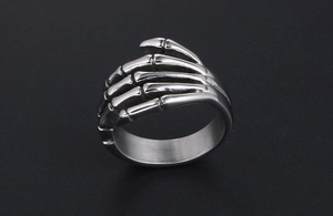 Macro shot of polished stainless steel punk skull hand ring with detailed bone structure