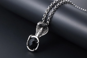 Detailed view of punk cobra pendant with black gemstone and silver cross engraving