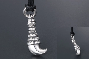 Macro detail of silver wolf tooth steel pendant with multi-layer carved texture and cord