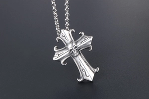 Detailed view of silver gothic cross pendant with skull motif and ornate carvings
