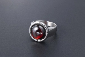 Gros plan d'une bague rétro en acier titane avec grand grenat rouge et texture dentée